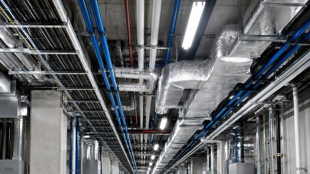 HVAC ventilation and pipe installation in building technical corridor with electrical and cable networks, representing engineering, infrastructure, air conditioning and maintenance.