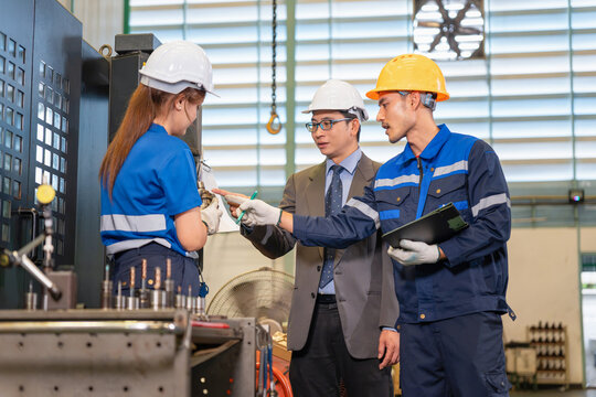 Manager and industrial workers discussing machine parts in factory workshop, Team of engineers and operators having technical meeting in manufacturing plant