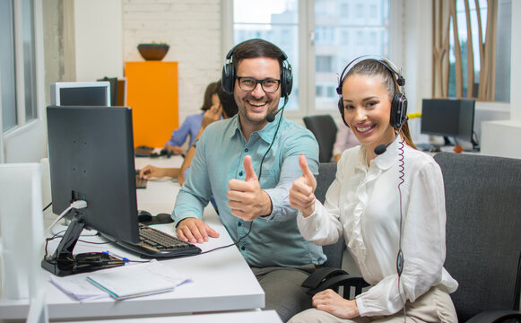 Happy customer service agents showing thumbs up sign for success