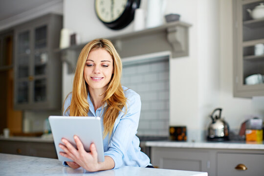 Smile, woman and reading at house with tablet, social media and browsing online for latest movies. Happy, person and rest in kitchen with digital app, internet search and streaming for film watchlist