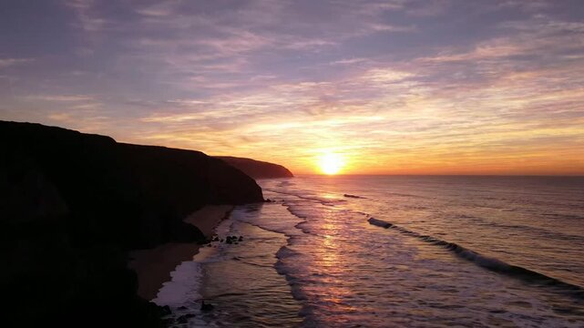 Aerial sunset over rugged coastal cliffs and rolling ocean waves serene golden hour seascape drone coastline