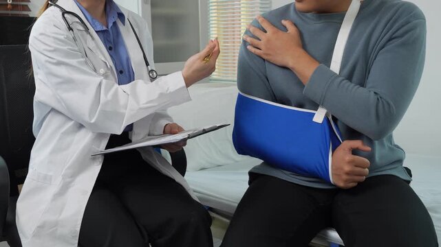 Doctor examining patient with broken arm and shoulder injury