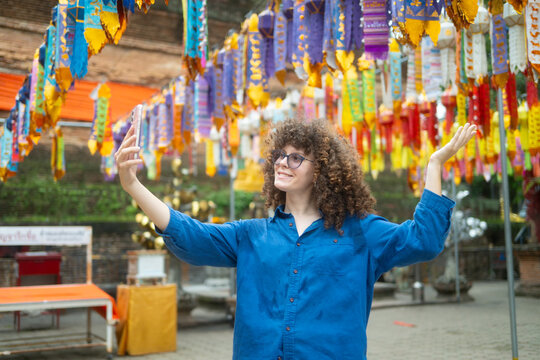 Caucasian Woman Taking Selfie at Thai Temple with Colorful Decorative Flags in Chiang Mai Thailand