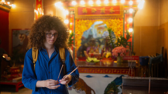 Caucasian Woman Holding Incense Sticks at a Chinese Buddhist Temple During Travel in Asia