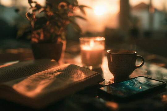 Cozy evening with book cup candle and phone warm golden light