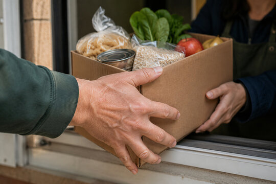 Hands exchanging a box of groceries as part of a community food donation and charity support program