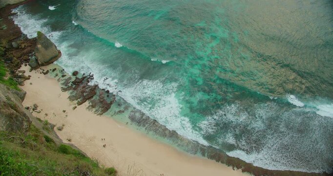 Ocean waves wash over coral reefs at base of limestone cliffs on Nusa Penida Island Bali coast