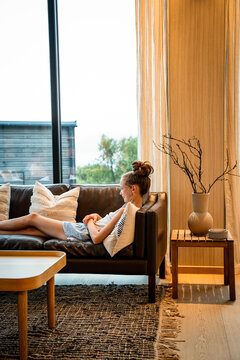 Young girl relaxing on a leather sofa at home