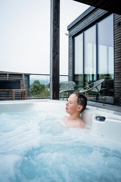 Young boy relaxing peacefully in an outdoor hot tub