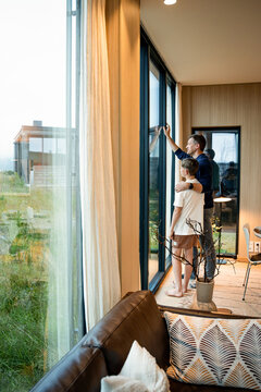 Father and son looking out window of modern home