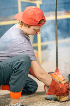 Glassblower carefully shaping molten glass in workshop
