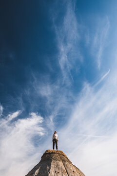 Woman stands on a small peak under a vast sky T.R. National Park