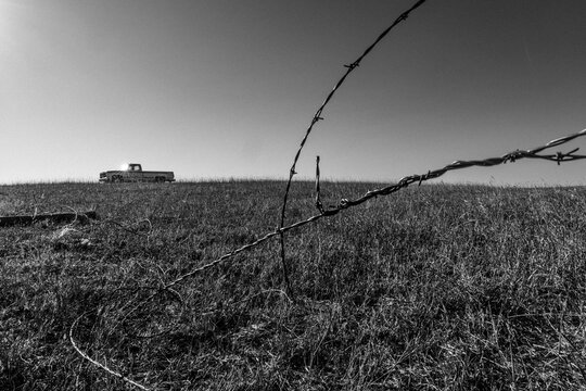 Barbed wire fence with an old truck on a hill