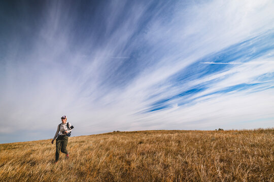 Woman hikes through golden grass under big sky