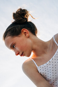 Low angle shot of a girl with freckles and a messy bun