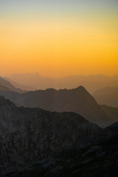 Mountain silhouettes layered in golden sunset haze