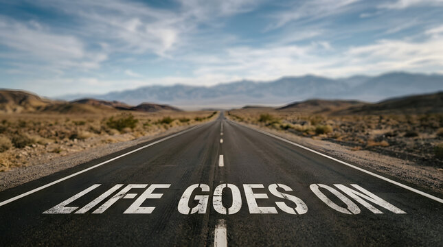 Road with motivational message extending into distant mountains