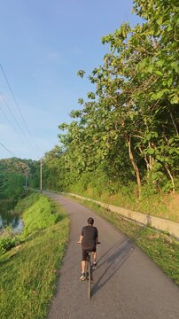 Person Cycling on a Scenic Road Beside a Lake