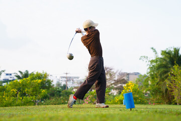 Fototapeta premium Asian golfer performing tee off shot on green course during game