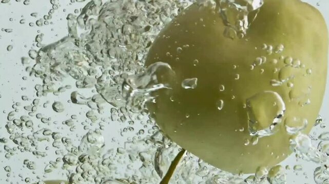 Green apples plunging deep underwater with bubbles