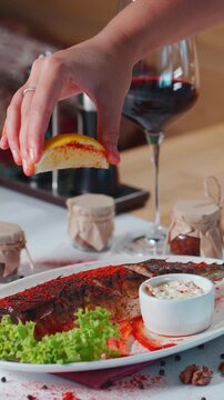 hand sprinkle baked mackerel fish with red paprika and lemon juice in restaurant