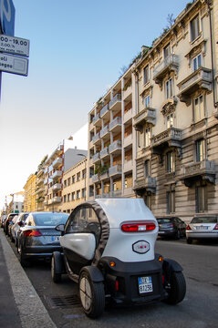 Milan, Italy - January 16 2019: Compact electric microcar parked on a street surrounded by conventional cars and historic residential architecture. Electric mobility in a dense European city.