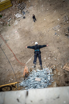 Person rope jumping with arms spread landing over pile of scrap metal rods, extreme sport adrenaline and thrill concept