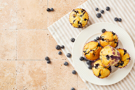 Homemade blueberry muffins on plate with striped napkin top view