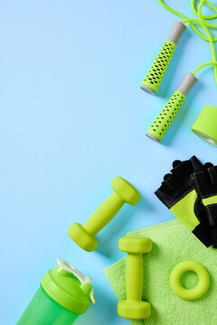 Green fitness equipment flat lay on blue background bottom right.