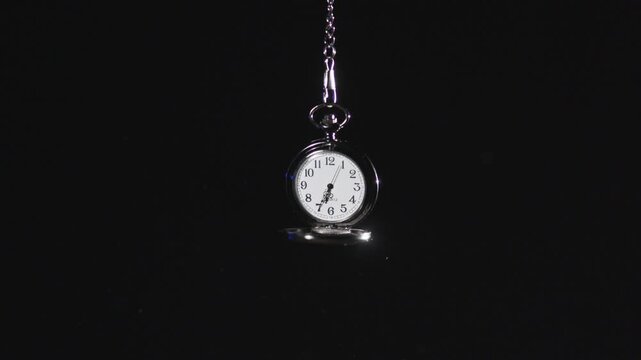 A stopwatch hangs in a dark void as the second hands tick in slow motion.