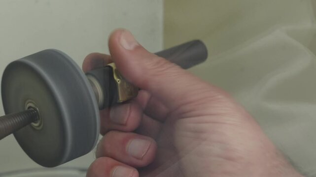Craftsman hands holding a rotary polishing wheel on a flex shaft at a jewellery bench