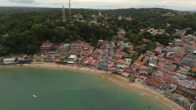 Aerial drone tilt up and zoom out revealing the beautiful First Beach and coastal village in Morro de Sao Paulo Bahia Brazil