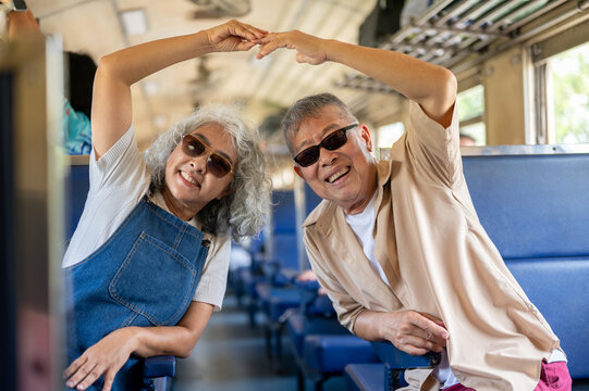 Asian senior elderly couple forming a heart with hands above their heads during a vintage train ride