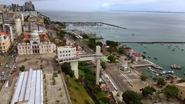 Aerial drone orbit revealing the Lacerda Elevator historic Mercado Modelo and boats in the beautiful Todos os Santos Bay in Salvador Bahia Brazil