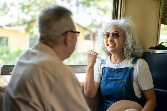 Asian senior couple talking and enjoying the scenery during a train journey