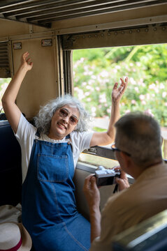 Asian senior woman photographing scenery from a train window during a joyful journey