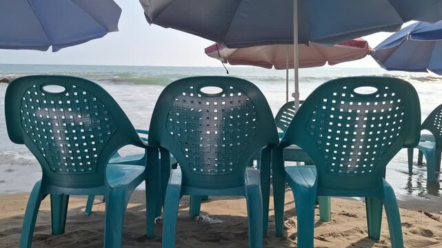 Blue Plastic Chairs and Beach Umbrellas on Sandy Seashore Facing Ocean View for Tropical Vacation and Coastal Tourism Concept