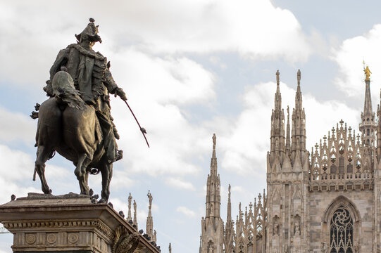 Milan, Italy - January 16 2019: Equestrian monument to King Victor Emmanuel II beside the ornate Gothic spires and sculptures of Milan Cathedral, Duomo di Milano, under a bright cloudy sky