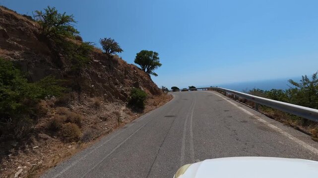 White car driving slowly on a narrow dangerous mountain road on the island of Crete, Greece