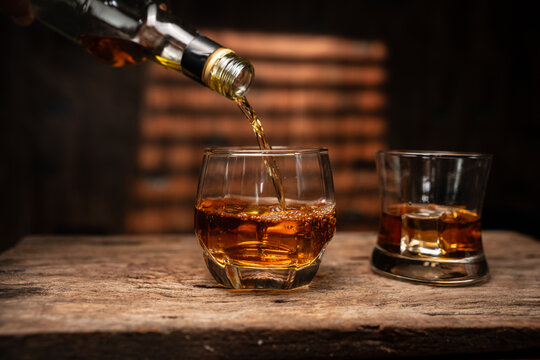 Pouring Whiskey into Glass on Wooden Table in Bar