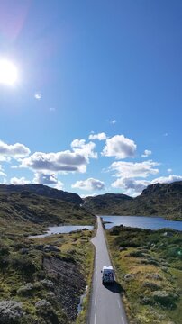 Aerial video of a scenic highway winding through the mountainous landscape of Norway, passing alpine lakes, rugged terrain and expansive Nordic wilderness, 4k.