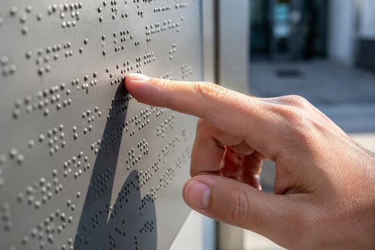 Close up of a person reading tactile Braille text with a finger, illustrating visual impairment, accessible communication, inclusive education, literacy and assistive technology
