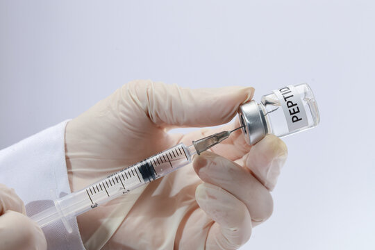 Professional doctor preparing peptide syringe for wellness therapy with focused calm expression in laboratory setting