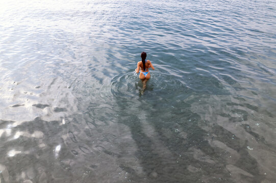 Woman wading into the clear blue sea water during a relaxing summer holiday on the coast of Torrox, Andalucia