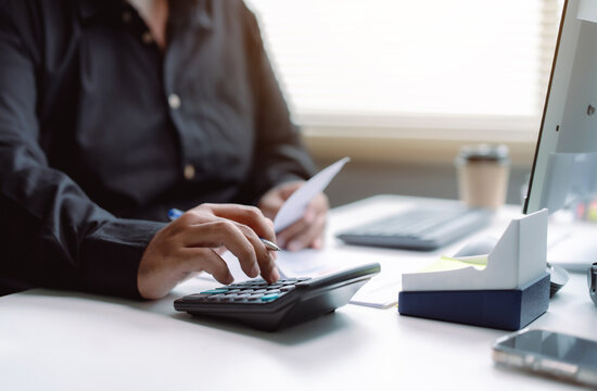 Accountant using calculator for financial analysis at office desk for professional audit and business management