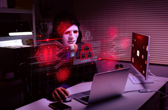 Cyber security hacker wearing white mask using laptop in dark room with glowing digital threat interface for computer safety and data protection concept