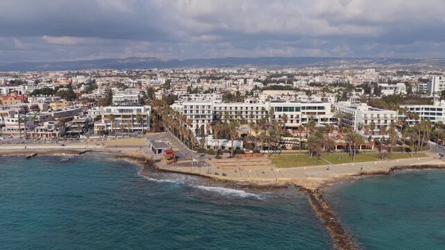 Aerial view of a modern resort town with white buildings along the coastline and turquoise sea.