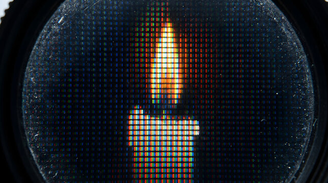 Extreme macro of pixels forming a candle flame on a digital screen through a lens.