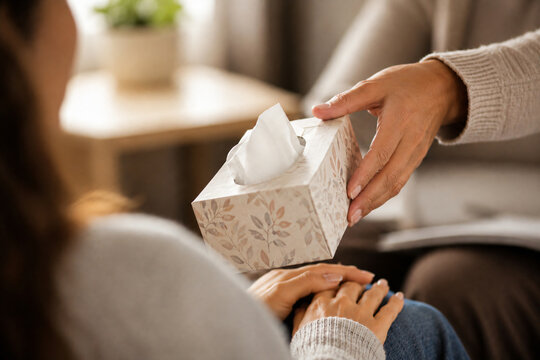 Counselor offering tissues to a person during an emotional therapy session, representing empathy, support and mental health care