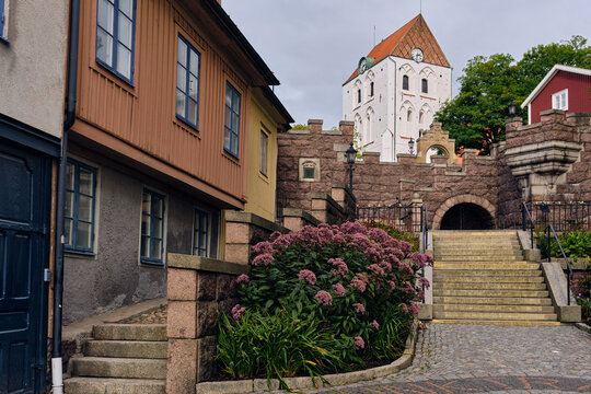 Historic architecture and charming old town square in Ronneby Sweden with Heliga Kors kyrka tower and traditional houses Stone walls steps and lush foliage create a picturesque urban landscape
